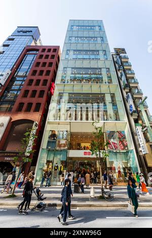 Das Flaggschiff Ginza Uniqlo Modegeschäft. Ladenvorderseite mit Schaufensterauslagen auf sechs Etagen, Eingang und Bürgersteig voll mit Menschen draußen. Stockfoto