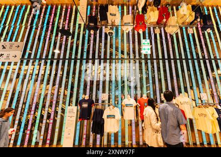 Ein japanisches Paar, das sich die T-Shirts an der Spiegelwand im Uniqlo-Laden auf der Ginza ansieht. Stockfoto