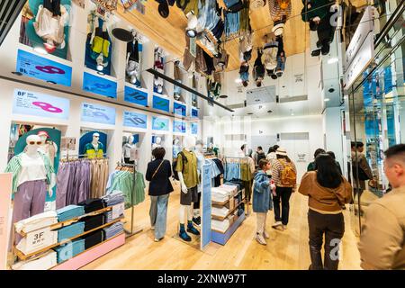 Shopper stöbern unter einer verspiegelten Decke durch Kleidung in der lässigen Herrenmode im Uniqlo Flagship Store auf der Ginza. Stockfoto