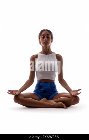 Junge farbige Frau in tiefer Meditation, sitzend in Lotusposition mit offenen Handflächen. Achtsamkeit, Aufgeschlossenheit und innere Ruhe auf einem Weißen demonstrieren Stockfoto