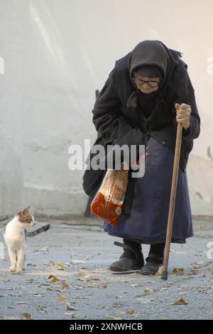 Eine hundertjährige Frau geht langsam, auf ihrem Stock gebeugt, Kloster Vracevsnica, Gornji Milanovac, Zentralserbien (Katze) Stockfoto