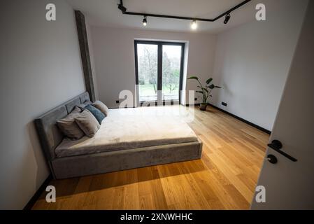 Schlafzimmer mit einem großen, komfortablen Bett. Innenausstattung eines neu gebauten Hauses, Schlafzimmer mit einem großen, komfortablen Bett mit weichen Kissen und weicher Bettwäsche, komplett Stockfoto