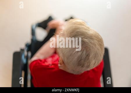 Blick von oben auf ältere Frau mit weißen Haaren und im Rollstuhl sitzend. Stockfoto