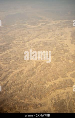 Ein Luftbild in großer Höhe von einer weitläufigen Wüste im Oman, das komplizierte natürliche Muster und eine trockene Landschaft einfängt. Dieses Bild kann als Metapher für Isolation, Widerstandsfähigkeit und Schönheit in Einfachheit dienen. Stockfoto