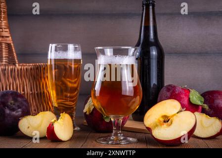 Gläser mit Sour Sweet Fruit Apple Craft Beer, Cider oder Ale auf Holztisch mit frischen roten Apfelscheiben Stockfoto