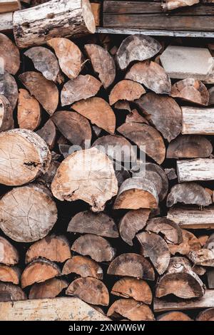 Ländlicher Hintergrund mit Holzstapel. Gehäckseltes Holz, gestapelt auf einem Stapel. Vorbereitung auf den kalten Winter. Heizung des Hauses mit natürlichem Brennstoff. Stockfoto