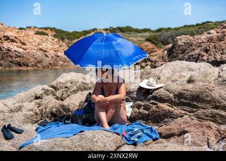 Frau mit Hund unter einem Sonnenschirm am Strand, Sardinien, Italien, Mittelmeer, Europa Stockfoto