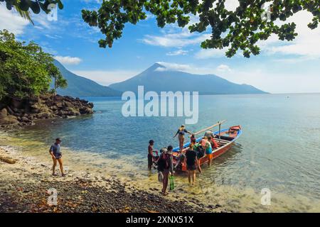 Touristen, die eine Bootsfahrt vom Kalea Beach mit aktivem Karangetang Vulkan jenseits von Kalea, Siau Island, Sangihe Archipel, Nord-Sulawesi Unternehmen Stockfoto