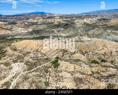 Trockene Wüstenlandschaft mit zerklüfteten Hügeln und einer Straße unter klarem Himmel, aus der Vogelperspektive, Tabernas-Wüste, Desierto de Tabernas, Tabernas, Almeria Stockfoto