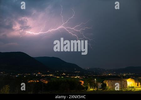 Ein Blitz mit vielen Seitenästen spaltet den Himmel über den Bergen der italienischen Alpen Stockfoto