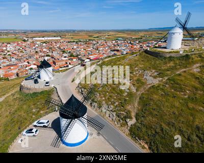 Luftaufnahme der Windmühlen auf Hügeln mit einer Stadt im Hintergrund an einem sonnigen Tag, Luftaufnahme, Consuegra, Toledo, Castilla-La Mancha, Spanien Stockfoto