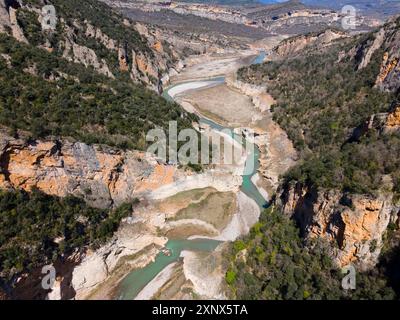 Aus der Vogelperspektive auf eine felsige Schlucht mit einem sich windenden Fluss und dicht bewachsenen Klippen, aus der Vogelperspektive auf die Schlucht Congost de Mont-rebei, Noguera Ribagorcana Stockfoto