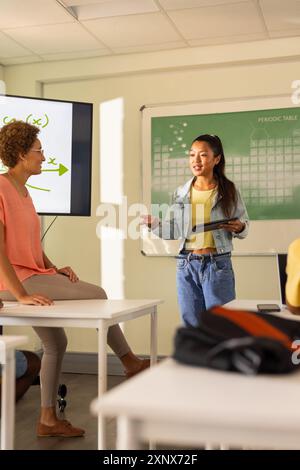 In der Highschool präsentierte sich ein Teenager mit Tablet im Klassenzimmer und sprach mit dem Lehrer Stockfoto