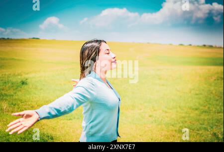 Glückliches Mädchen, das Arme spreizt, atmet frische Luft auf dem Feld. Entspannte Frau, die an einem sonnigen Tag frische Luft in einem schönen Feld atmet Stockfoto