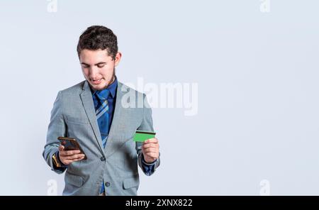 Junger Geschäftsmann, der Handy und Kreditkarte isoliert hält. Gutaussehender Mann mit Kreditkarte und Handy in der Hand isoliert, Bankzahlung online Stockfoto