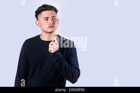 Junger Mann, der sich mit Hand am Kinn fragt. Mann denkt mit Hand am Kinn isoliert Stockfoto