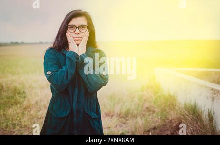 Porträt einer schönen Frau mit Brille auf dem Feld. Niedliches Mädchen in Brille mit Händen auf den Wangen draußen Stockfoto