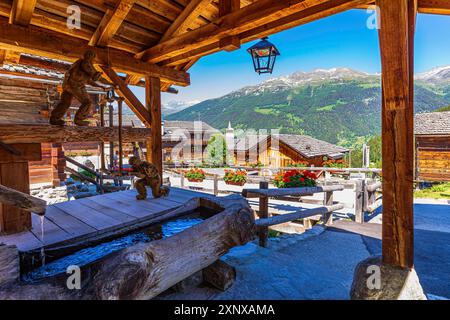 Holzskulpturen mit Sägewerk-Motiven auf dem Dorfplatz, dem historischen Ortskern, Grimentz, Val d'Anniviers, den Walliser Alpen, Kanton Wallis Stockfoto