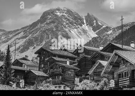 Eingebettete alte Holzhäuser, im Hintergrund der Gipfel des Berges Scex de Marenda, historisches Dorfzentrum, Schwarz-weiß-Foto Stockfoto