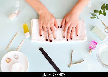 Draufsicht der Ernte anonyme Frau mit dunkler Maniküre sitzen am Tisch mit verschiedenen Werkzeugen während der professionellen Maniküre Verfahren im Spa-Salon Stockfoto