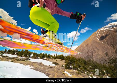 Mädchen im Flug, nachdem sie im Frühjahr vor der Kulisse der Berge und des blauen Himmels von einem Kicker gesprungen sind. Nahaufnahme Weitwinkel. Das Konzept von Stockfoto