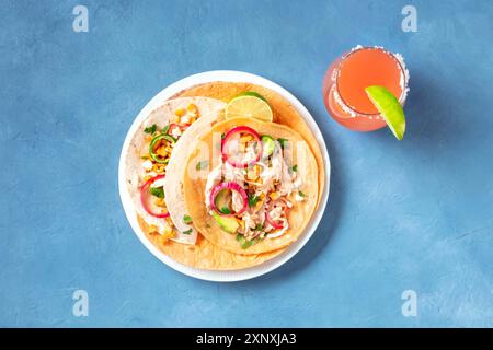 Mexikanische Tacos, Tortillas mit Hühnerfleisch, Avocado, Mais und Zwiebeln, mit dem Paloma-Cocktail, von oben geschossen Stockfoto