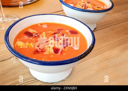 Salmorejo, spanische kalte Tomatensuppe in einer rustikalen Schüssel auf einem Holztisch Stockfoto