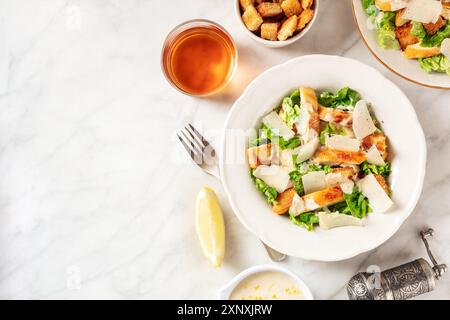 Caesar Salat mit der klassischen Soße und Wein, über dem Kopf flach lag auf einem weißen Marmor Hintergrund mit Kopierraum erschossen Stockfoto