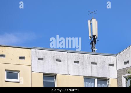 Mobilfunk-Basisstation-Antenne auf dem Telekommunikationsmast für die Mobilkommunikation auf dem Dach eines Mehrfamilienhochhauses gegen a b Stockfoto