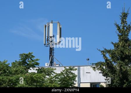 Mobilfunk-Basisstation-Antenne auf dem Telekommunikationsmast für die mobile Kommunikation auf dem Dach eines Wohngebäudes gegen eine blaue SK Stockfoto