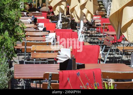 Einladende rustikale Möbel in einem Straßenrestaurant oder Café mit Holztischen und -Stühlen und roten Decken, Outdoor Gastronomie, ausgewählte Fokussierung, schmales de Stockfoto