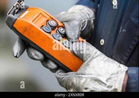 Handgriff-Fernbedienungsschalter für Deckenkran im Werk, Nahaufnahme. Elektrische Bedienkonsole des Krans und anderer Hebezeuge Stockfoto