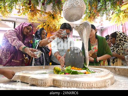 Neu-Delhi, Indien. August 2024. NEW DELHI, INDIEN – 2. AUGUST: Hindu-Anhänger und sein Familienmitglied schenken am 2. August 2024 in Neu-Delhi, Indien Milch und Wasser auf Shiva Linga auf dem Sawan Shivratri im Shivalaya-Tempel. (Foto: Sonu Mehta/Hindustan Times/SIPA USA) Credit: SIPA USA/Alamy Live News Stockfoto