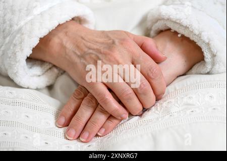 Nahaufnahme der Hände einer alten Frau, die eine übereinander gefaltet hat. Ältere Frau mit gefalteten Händen Stockfoto