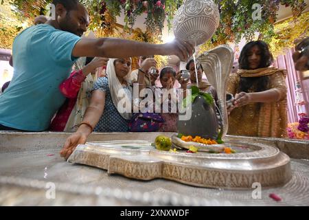 Neu-Delhi, Indien. August 2024. NEW DELHI, INDIEN – 2. AUGUST: Hindu-Anhänger und sein Familienmitglied schenken am 2. August 2024 in Neu-Delhi, Indien Milch und Wasser auf Shiva Linga auf dem Sawan Shivratri im Shivalaya-Tempel. (Foto: Sonu Mehta/Hindustan Times/SIPA USA) Credit: SIPA USA/Alamy Live News Stockfoto