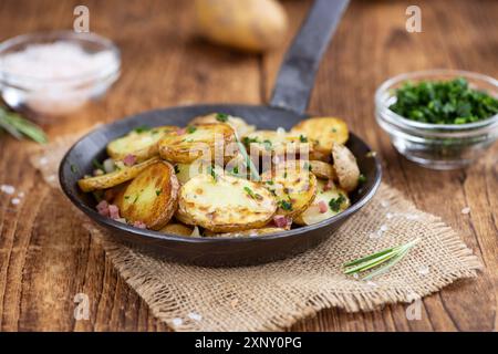 Gebratene Kartoffeln mit Zwiebeln und Schinken auf einem Holztisch (selektiver Fokus) Stockfoto