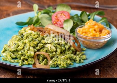 Spinatspätzle auf blauem Teller Stockfoto