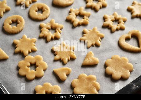 Verschiedene Formen aus rohem Teig auf einem Blatt Backpapier - Vorbereitung von Linzer Weihnachtskeksen Stockfoto