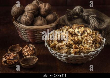 Walnüsse und Kerne in einem Korb auf dunklem Holzhintergrund Stockfoto