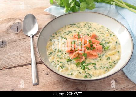 Hausgemachte vegetarische Cremesuppe aus Petersilienblättern und Kartoffeln mit Streifen Räucherlachs auf einem rustikalen Holztisch, Kopierraum, ausgewählter Fokus Stockfoto
