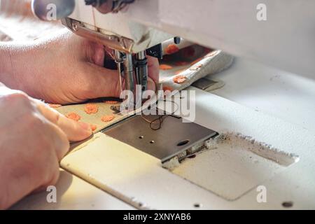 Innenarchitektin arbeitet an einer industriellen Nähmaschine mit Stoff für Polster, Vorhänge oder Wohndekoration Kopierraum, ausgewählter Fokus, schmal Stockfoto