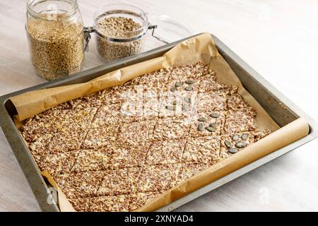 Backblech mit Teig aus Leinen- und Haferflocken, in Rauten geschnitten und mit verschiedenen Samen belegt für gesunde Gebäck Snacks, Kopierraum, ausgewählt Stockfoto