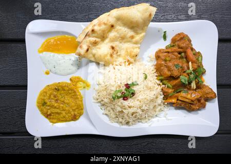 Indisches Fleischgericht aus Rindfleisch mit Soße, Reis, Brot, Linsen und Dips, serviert auf einem weißen Teller und einem dunklen Tisch, Blick von oben, ausgewählt Stockfoto