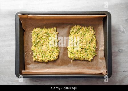 Teig Zucchini und Haferflocken als Basis für vegane Low Carb Pizza oder Gemüsekuchen auf einem Tablett mit Backpapier, Hochwinkelansicht von oben Stockfoto