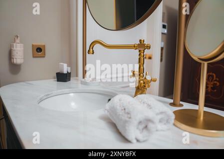 Luxuriöses Bad mit Ablagefläche aus weißem Marmor und goldfarbenen Akzenten Stockfoto