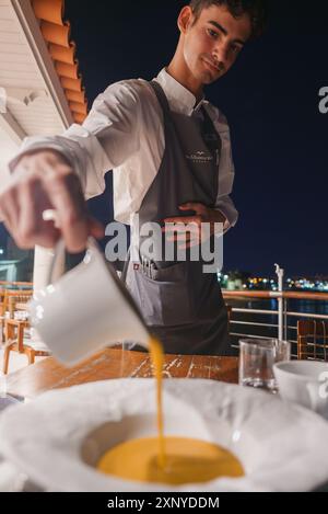 Kellner serviert cremige Suppe am eleganten Esstisch im Freien mit Blick auf die Stadt Stockfoto