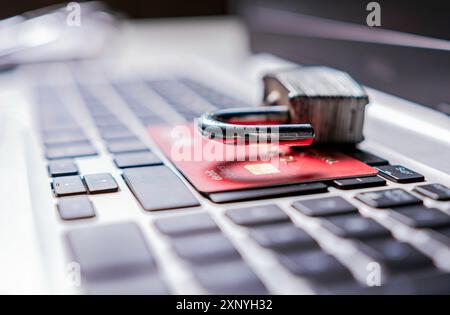 Öffnen Sie das Vorhängeschloss mit der Kreditkarte auf der Tastatur. Das Konzept des Diebstahls von Informationen auf Kreditkarten. Vorhängeschloss oben auf der Kreditkarte auf der Laptop-Tastatur Stockfoto