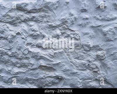 Eine alte weiße Steinmauer an einem Gebäude in der englischen Landschaft schafft ein interessantes strukturiertes grafisches Element, das als Hintergrundplatte verwendet werden kann. Stockfoto