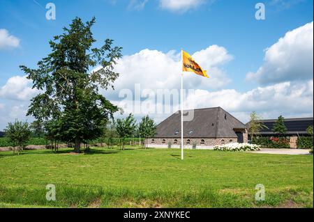 Wilbertoord, Nord-Brabant, Niederlande, 11. Juli 2024 - grünes Ackerland, Landhaus und gelbe Holland-Flagge Stockfoto