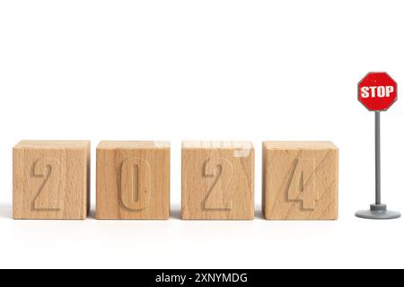 Holzwürfel mit Inschrift 2024 und Stoppschild auf weißem Hintergrund Stockfoto